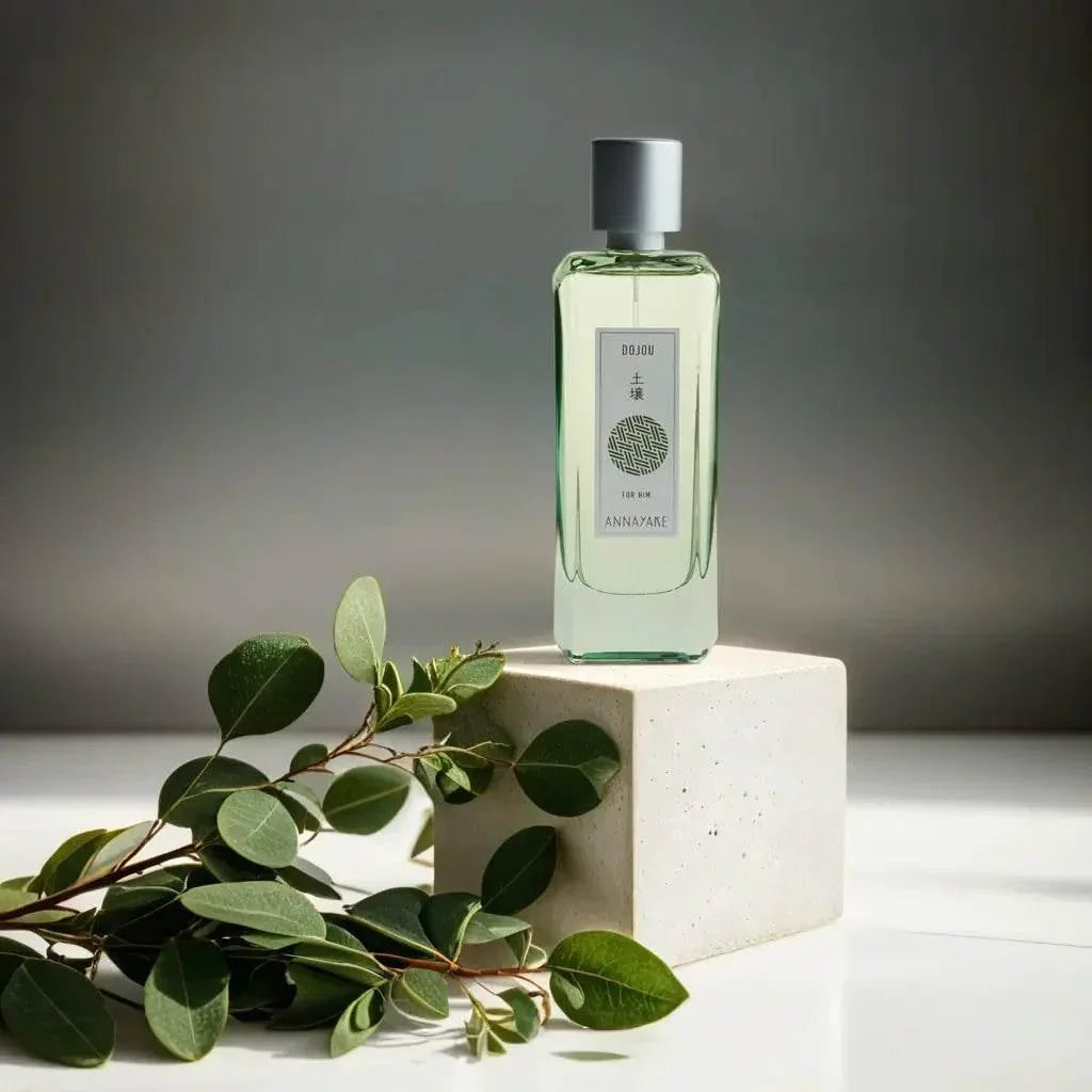 Herrenparfum Eau de Toilette Flakon mit silbernem Deckel neben grĂŒnen BlĂ€ttern, minimalistisch