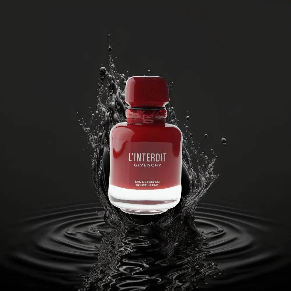 Rotes Parfumflakon L'Interdit Eau de Parfum auf schwarzem Hintergrund mit Wasserspritzern