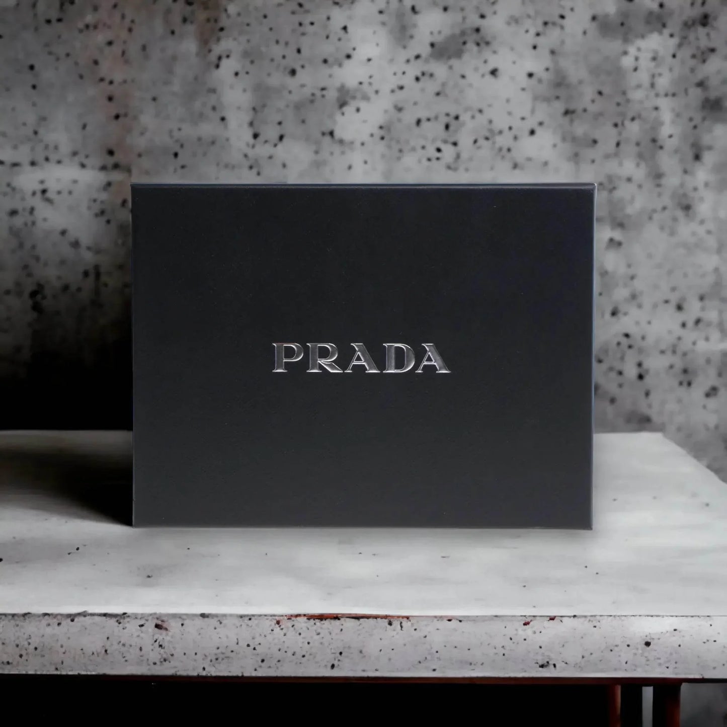Edle schwarze PRADA Geschenkbox, luxuriöses Parfum Set auf hellem Tisch vor Steinwand.