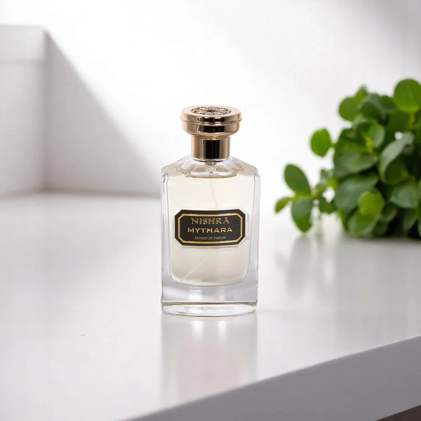 Luxus Parfumflakon Nishra Mythara auf heller Oberfläche mit grünem Pflanzenhintergrund