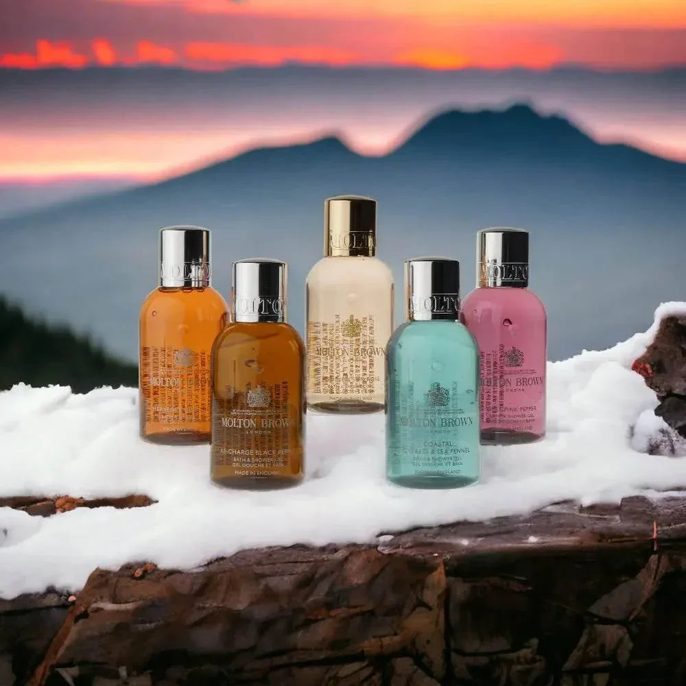 Molton Brown Reise-Körperpflege-Set auf verschneitem Baumstamm vor Sonnenuntergang