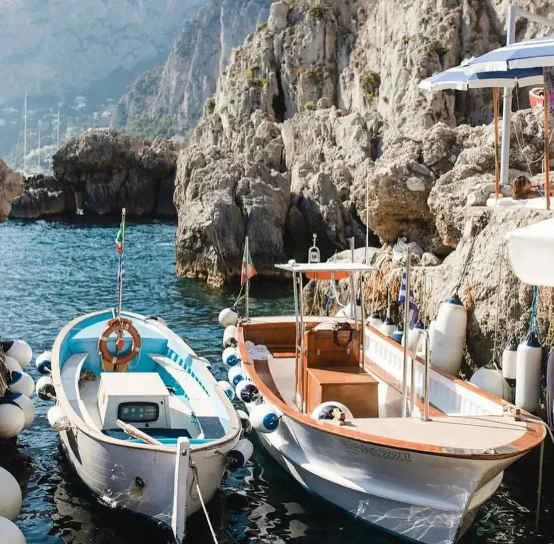 Zwei Boote im klaren Wasser vor steilen Felsen an der Amalfiküste, mediterrane Landschaft