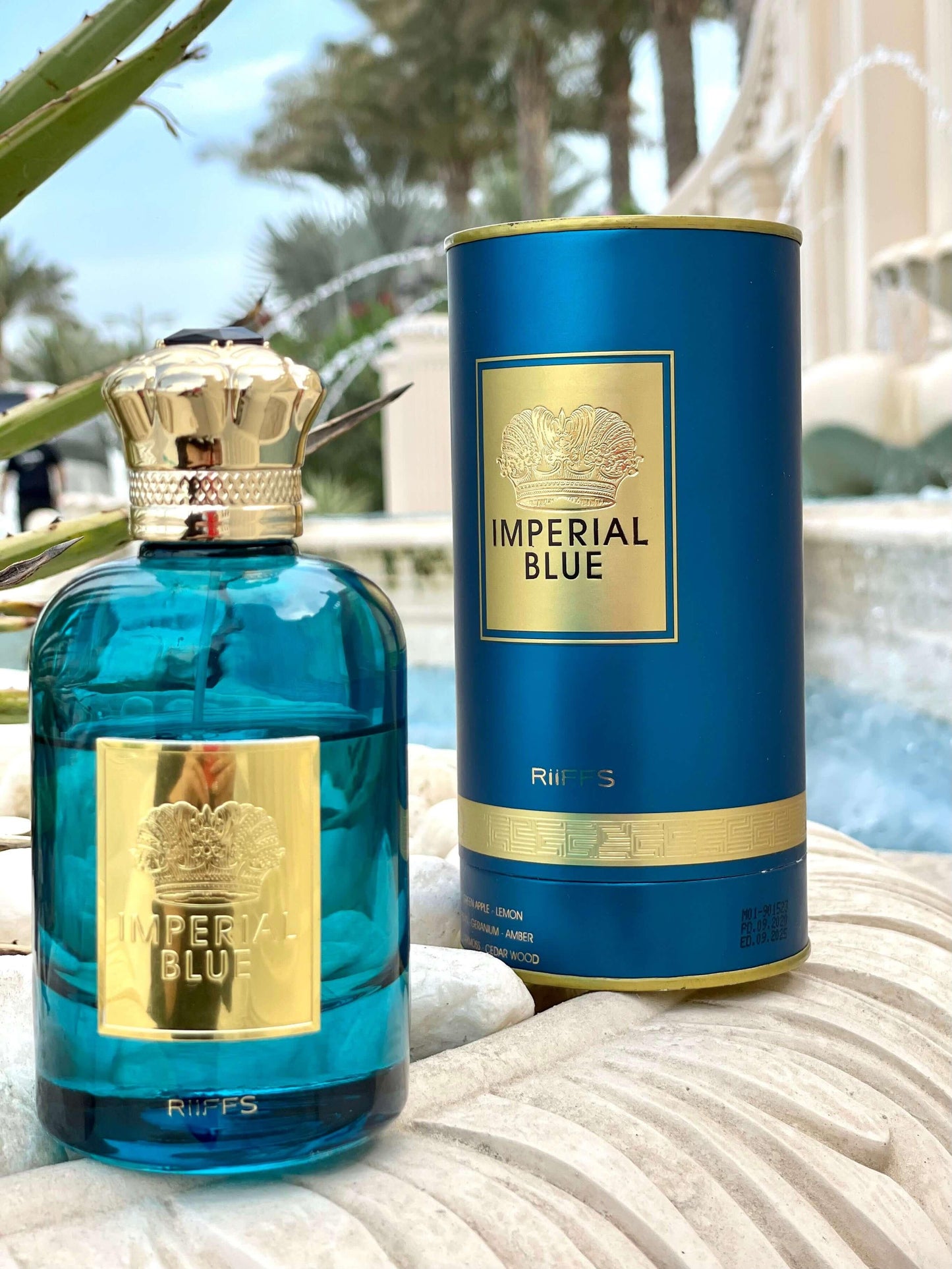 Imperial Blue Luxusparfum Flasche und Verpackung, gold-blaue Details, draußen vor Palmen