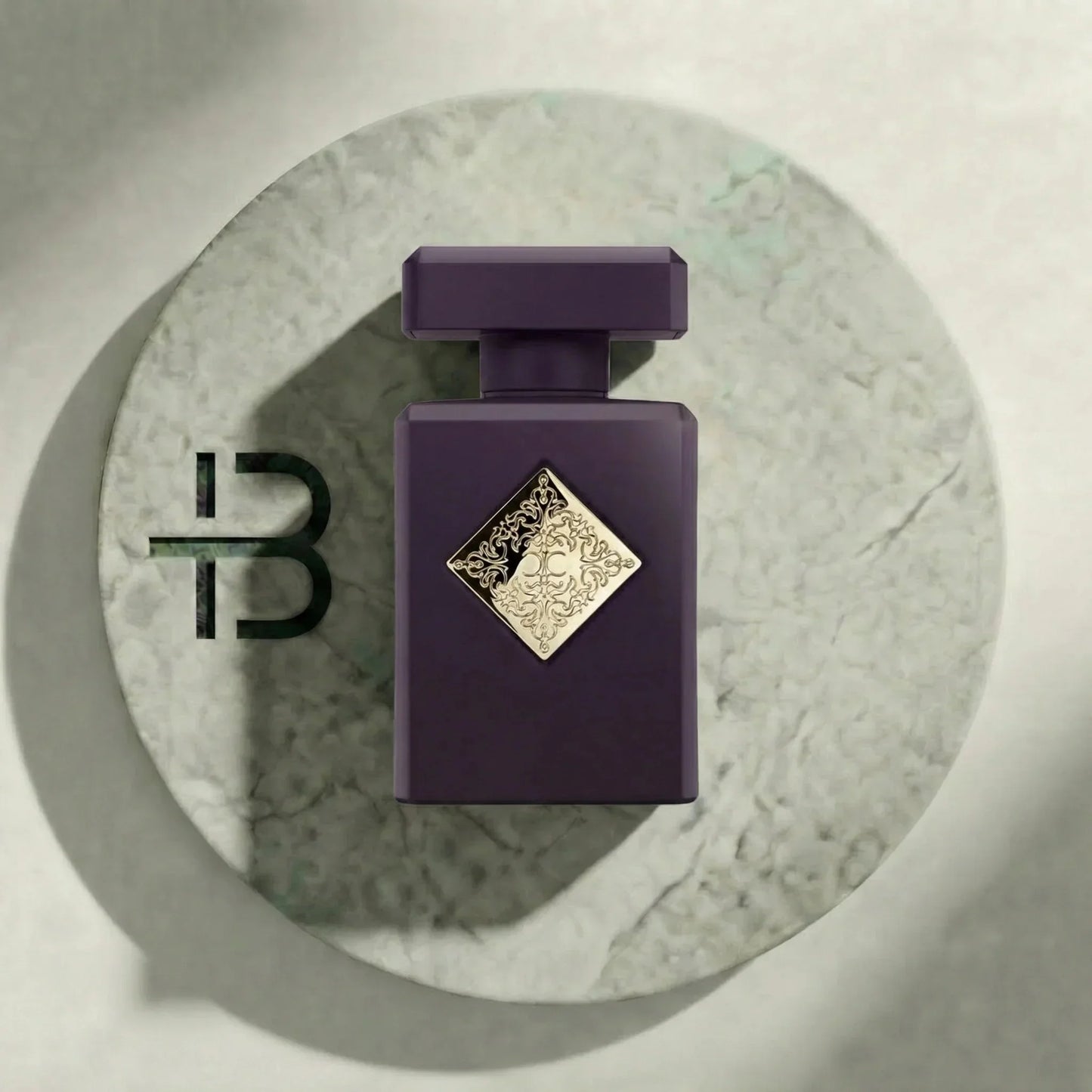 Luxuriöses Parfumflakon in dunklem Violett mit goldener Verzierung auf Marmorplatte