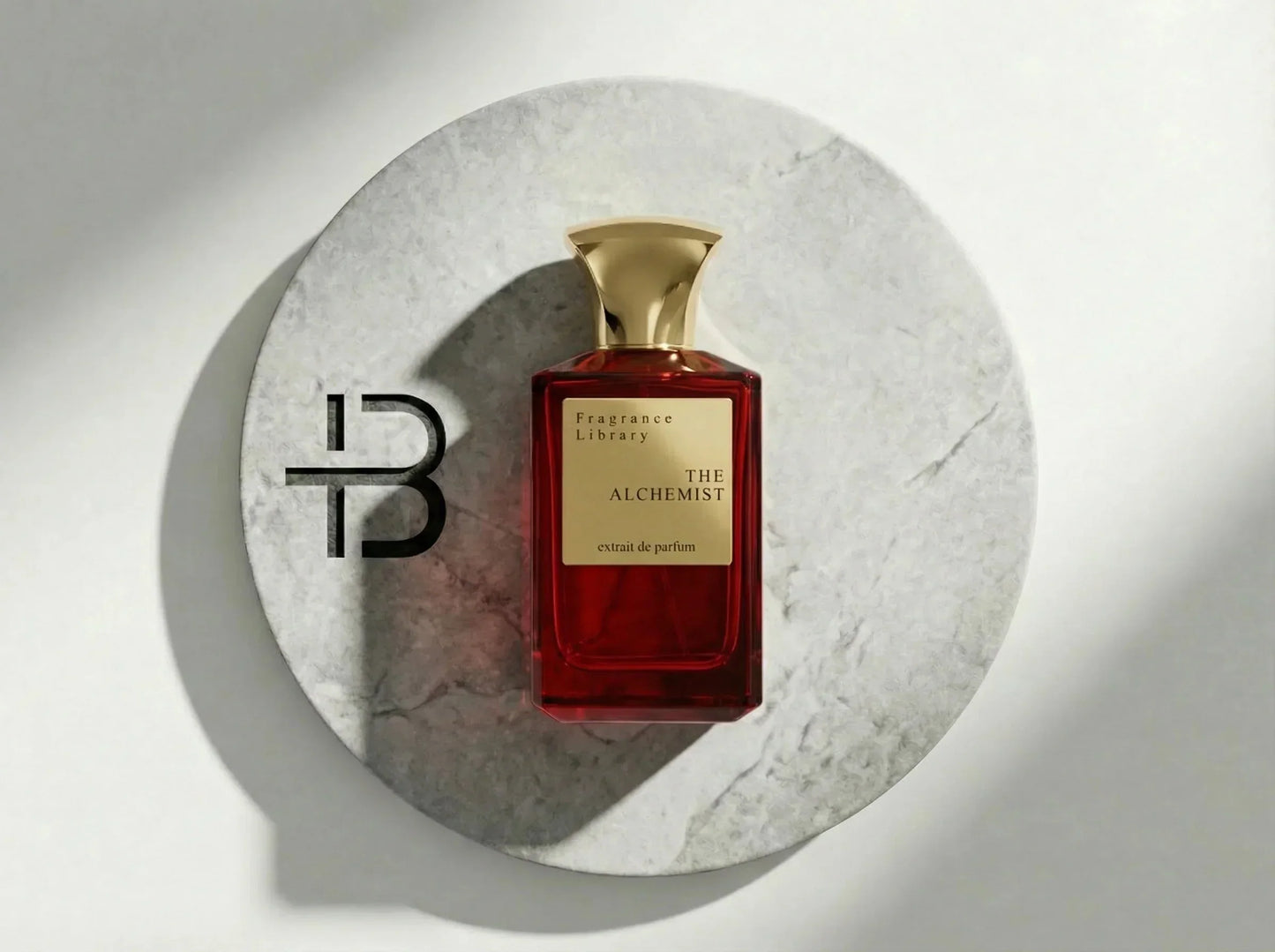Roter Luxusparfumflakon mit goldener Kappe auf rundem Marmortablett, Aufschrift The Alchemist.
