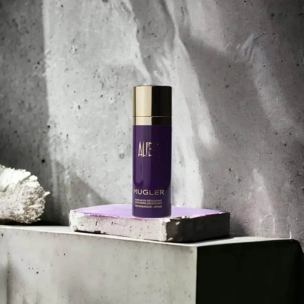 Lila Deospray-Flasche mit goldener Kappe von Mugler, auf Betonfläche stehend