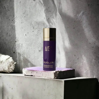 Lila Deospray-Flasche mit goldener Kappe von Mugler, auf Betonfläche stehend