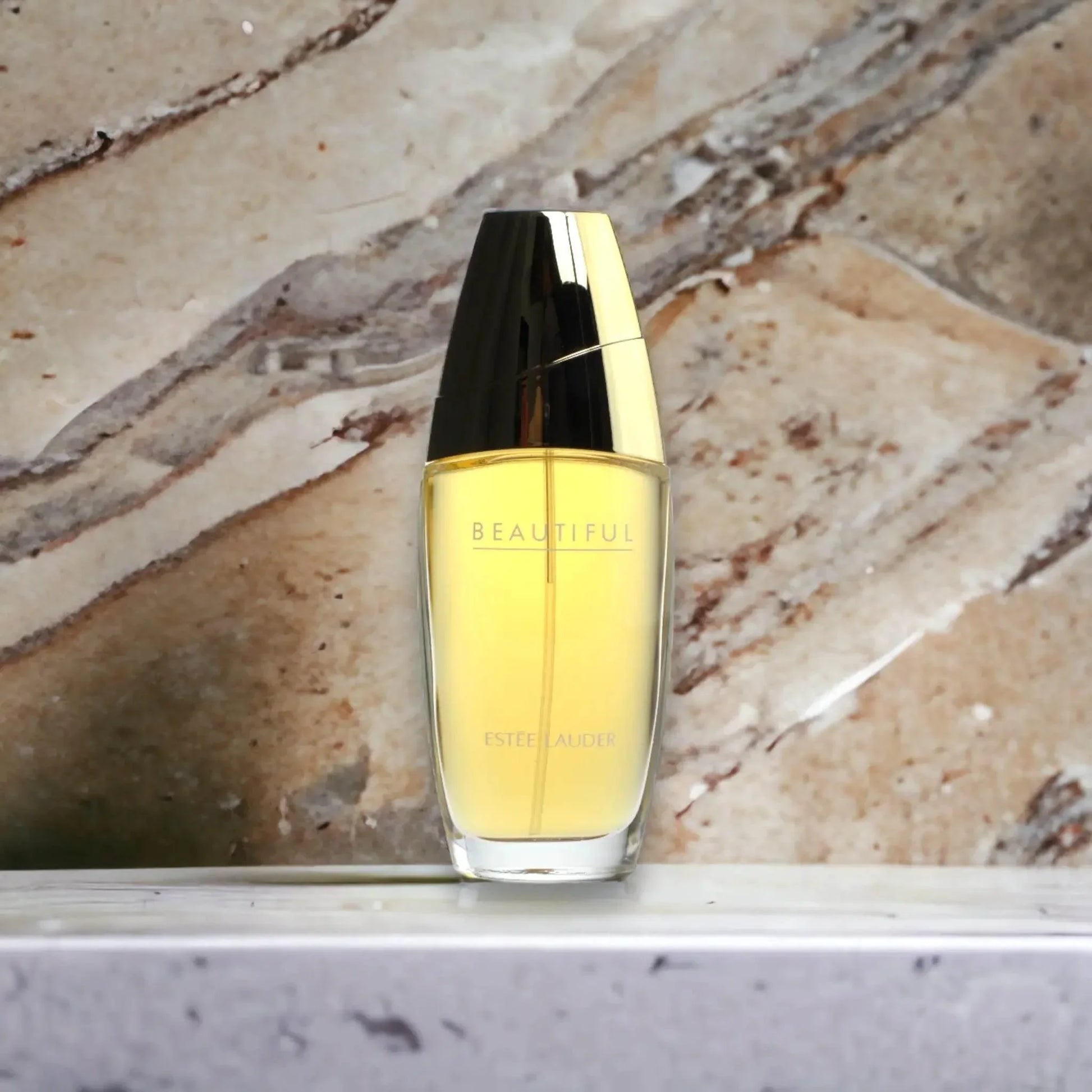 Elegantes Eau de Parfum in goldener Flasche auf Marmorhintergrund, Luxusduft für Damen