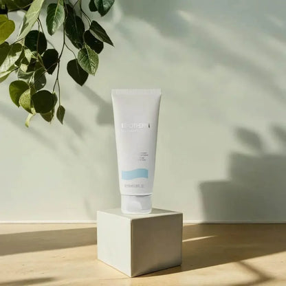 Biotherm Biomains Handcreme Tube auf elegantem Podest, Sonnenlicht, grüne Blätter, Hautpflege