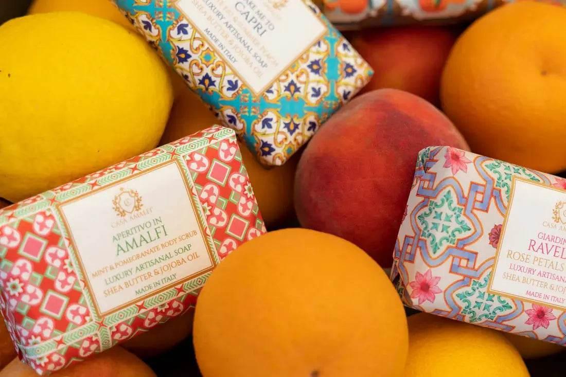 Bunte Luxus-Seifen mit dekorativen Verpackungen, umgeben von Zitrusfrüchten und Pfirsichen