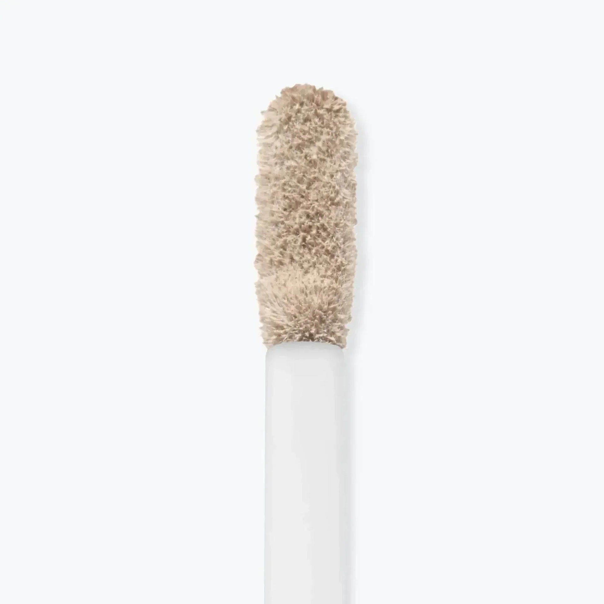 Detailaufnahme eines Concealer-Applikators mit cremiger, heller Make-up-Textur