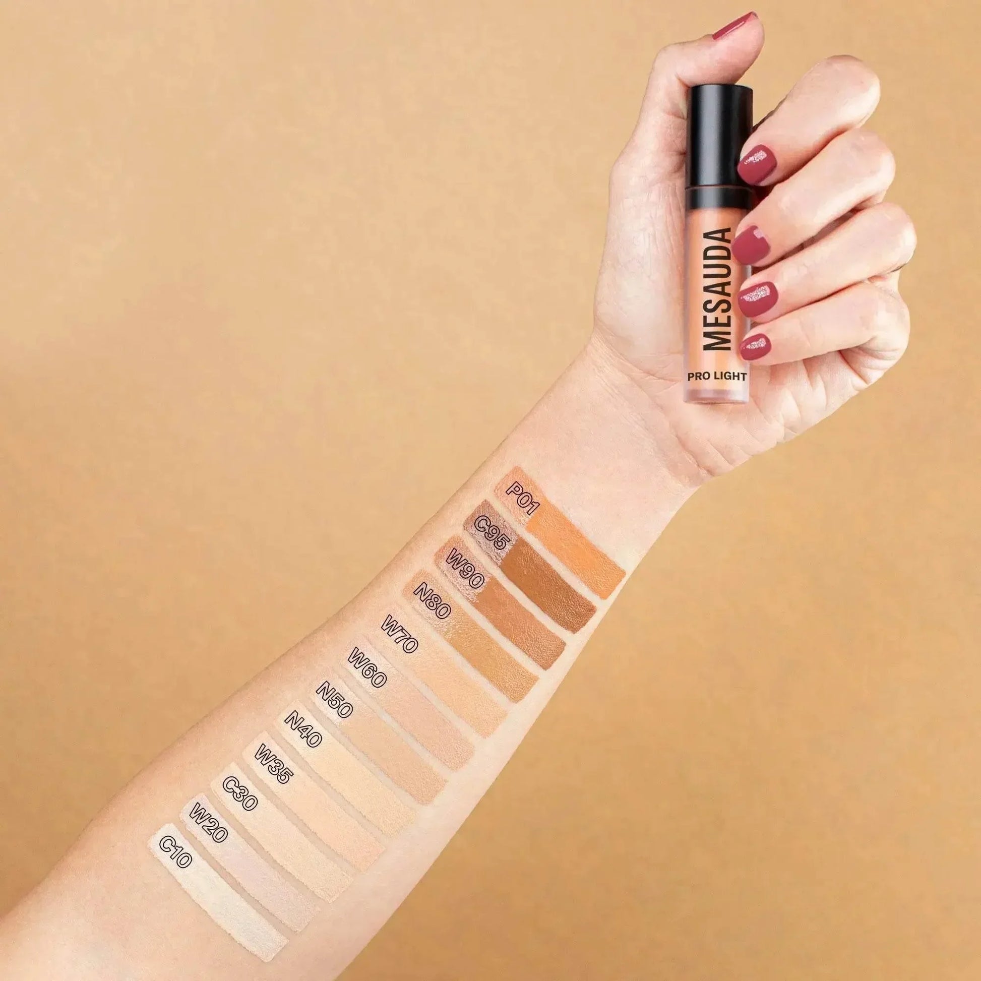 Concealer Flüssigtextur in Hand, verschiedene Farbnuancen als Swatches auf Unterarm, Make-up Produkt