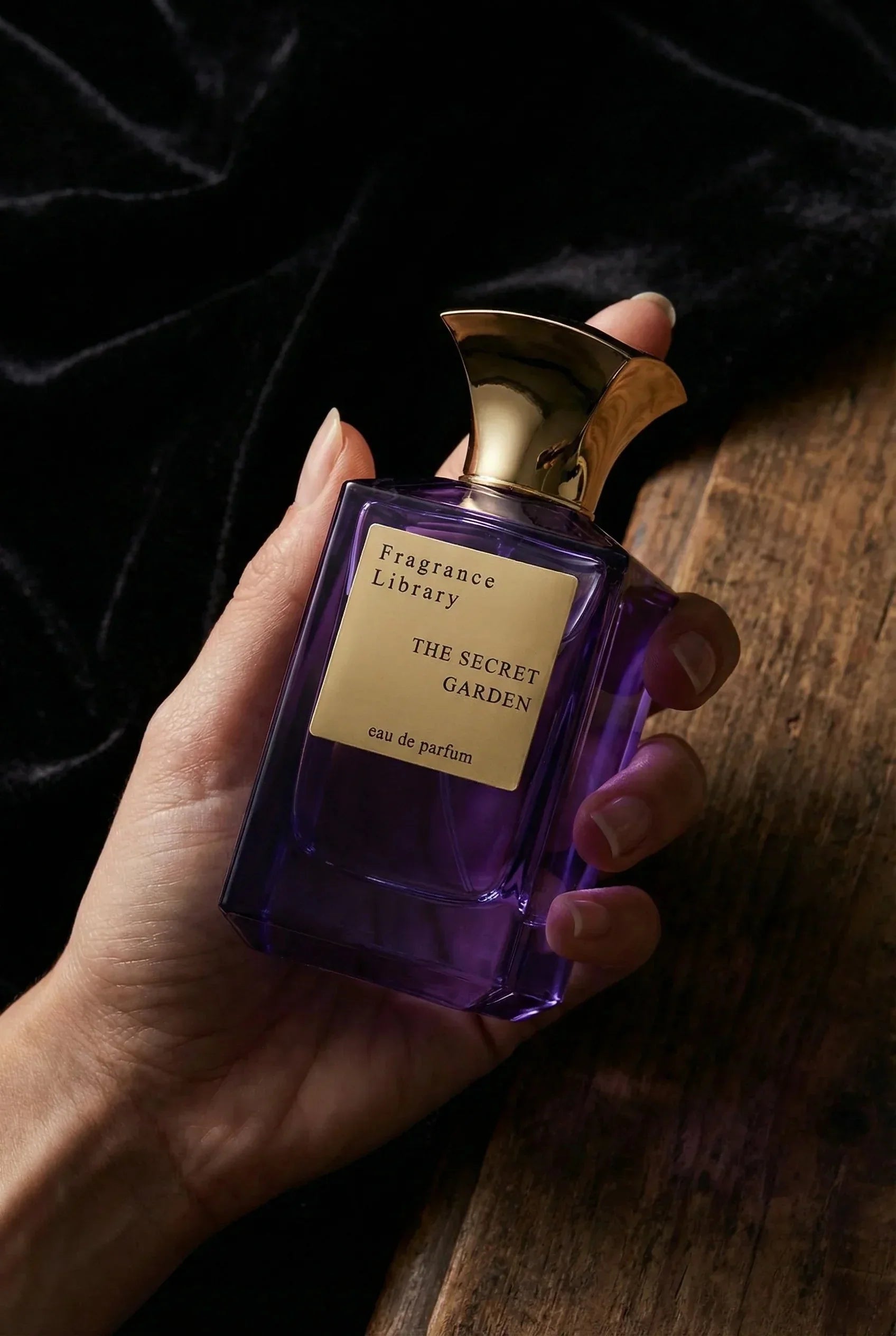 Luxusparfum Flakon violett mit goldenem Verschluss, Hand hält exklusives Eau de Parfum.
