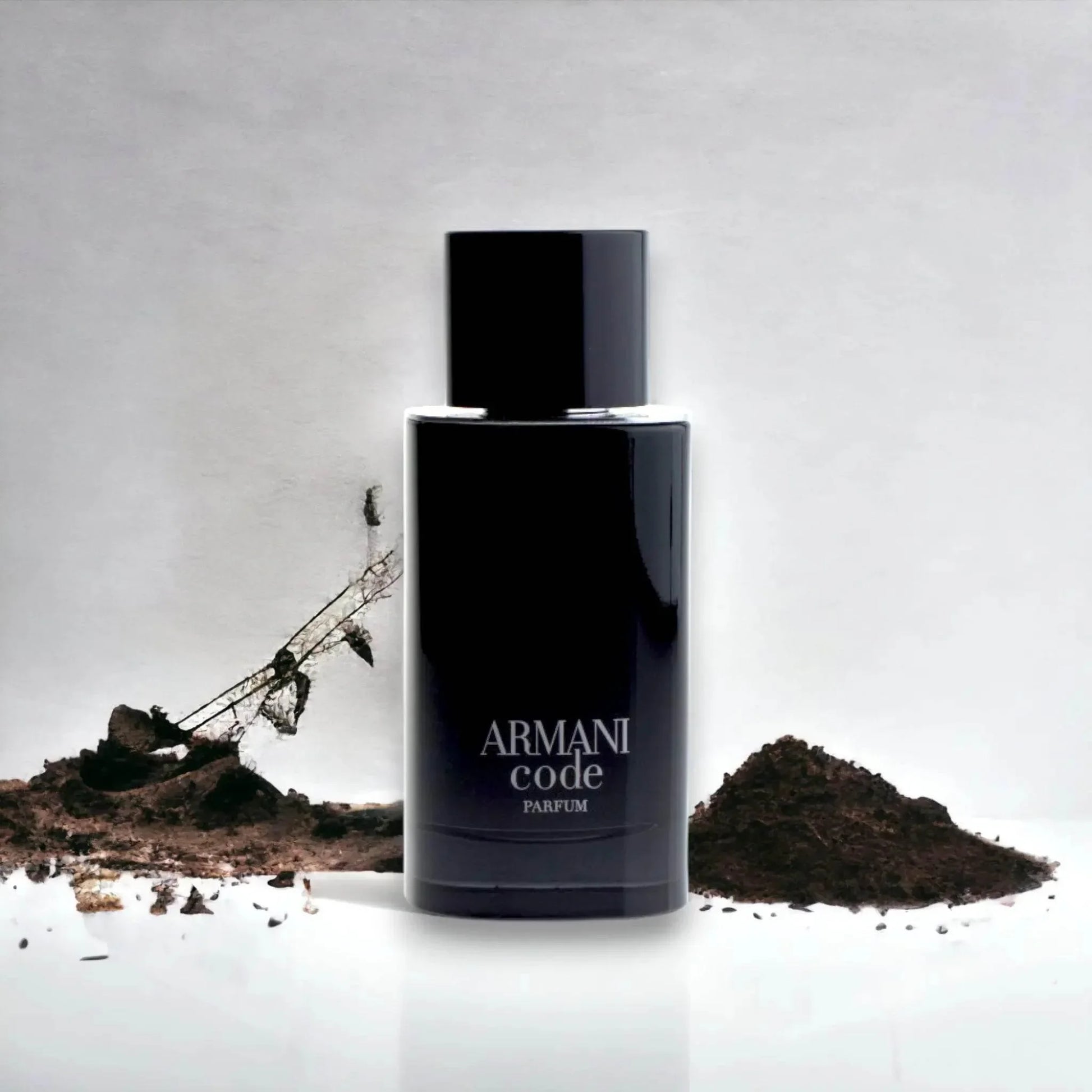 Schwarzer Parfumflakon Armani Code vor weißem Hintergrund mit Erde dekoriert, Luxusduft