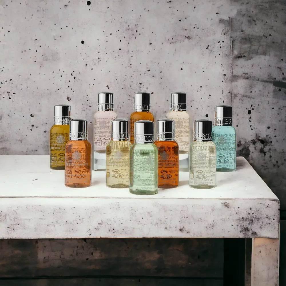 Neun bunte Body Care Duschgel Fläschchen auf weißem Tisch vor Betonwand, Beauty Pflege Set