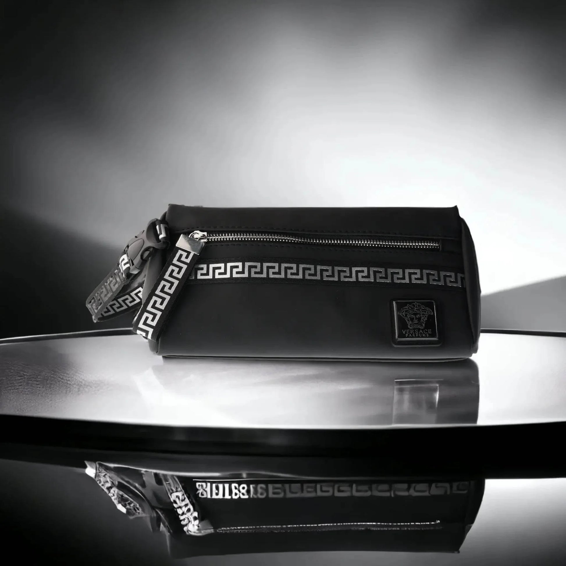 Elegante schwarze Kulturtasche mit Versace-Logo, griechischem Muster und Reißverschluss, stilvoll beleuchtet.