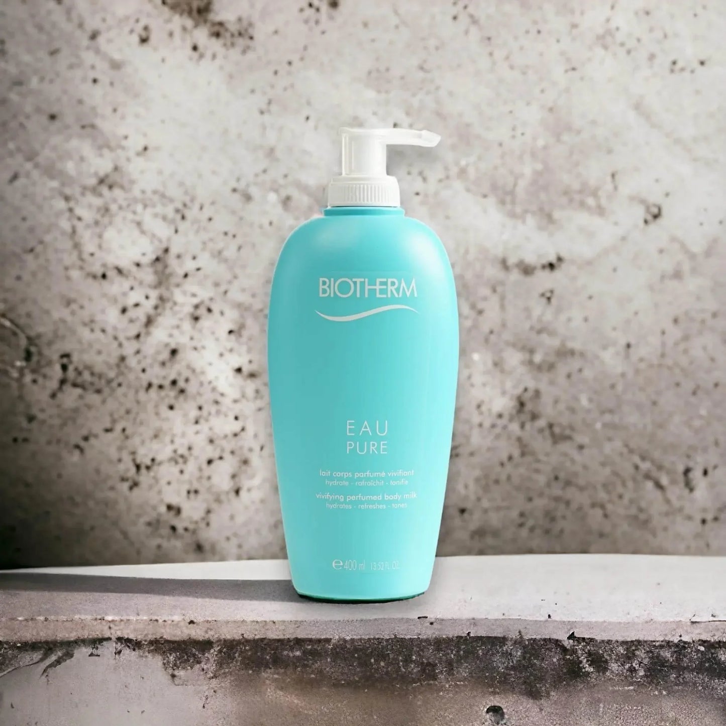 Eau Pure Body Milk in türkisfarbener Flasche mit Pumpspender auf Steinuntergrund