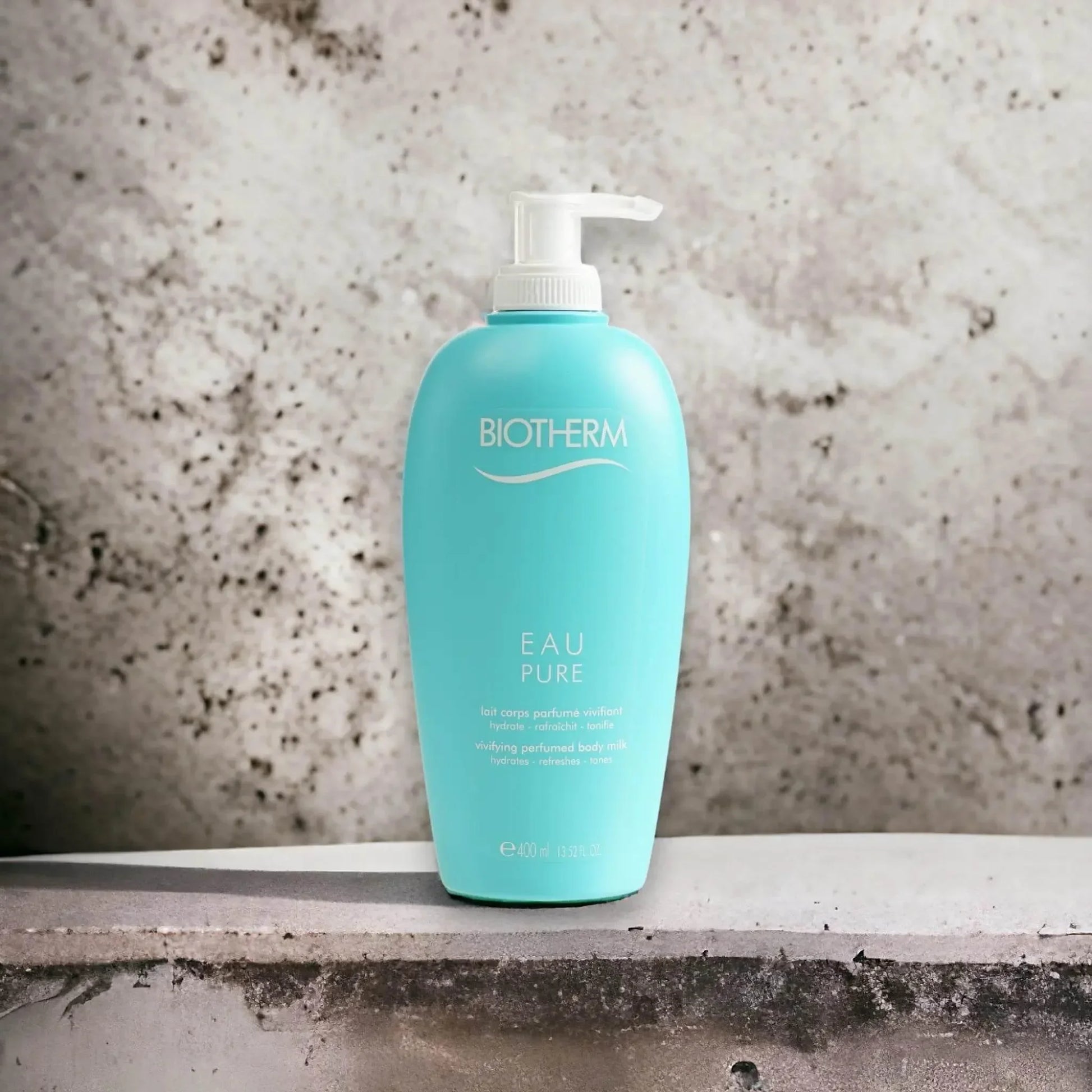 Eau Pure Body Milk in türkisfarbener Flasche mit Pumpspender auf Steinuntergrund