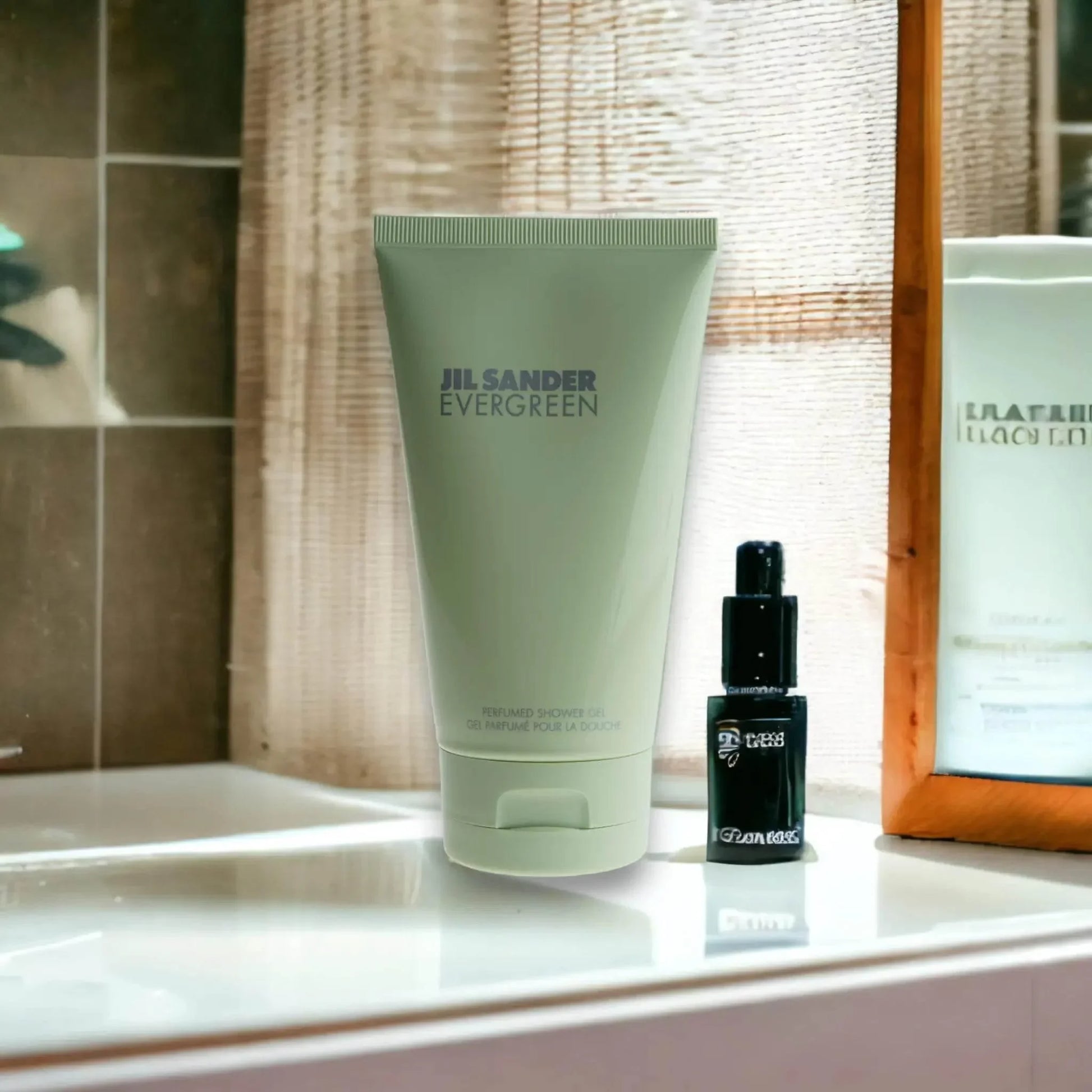 Jil Sander Evergreen Duschgel auf Badezimmerablage neben einem kleinen schwarzen Flakon