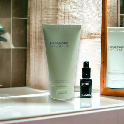 Jil Sander Evergreen Duschgel auf Badezimmerablage neben einem kleinen schwarzen Flakon