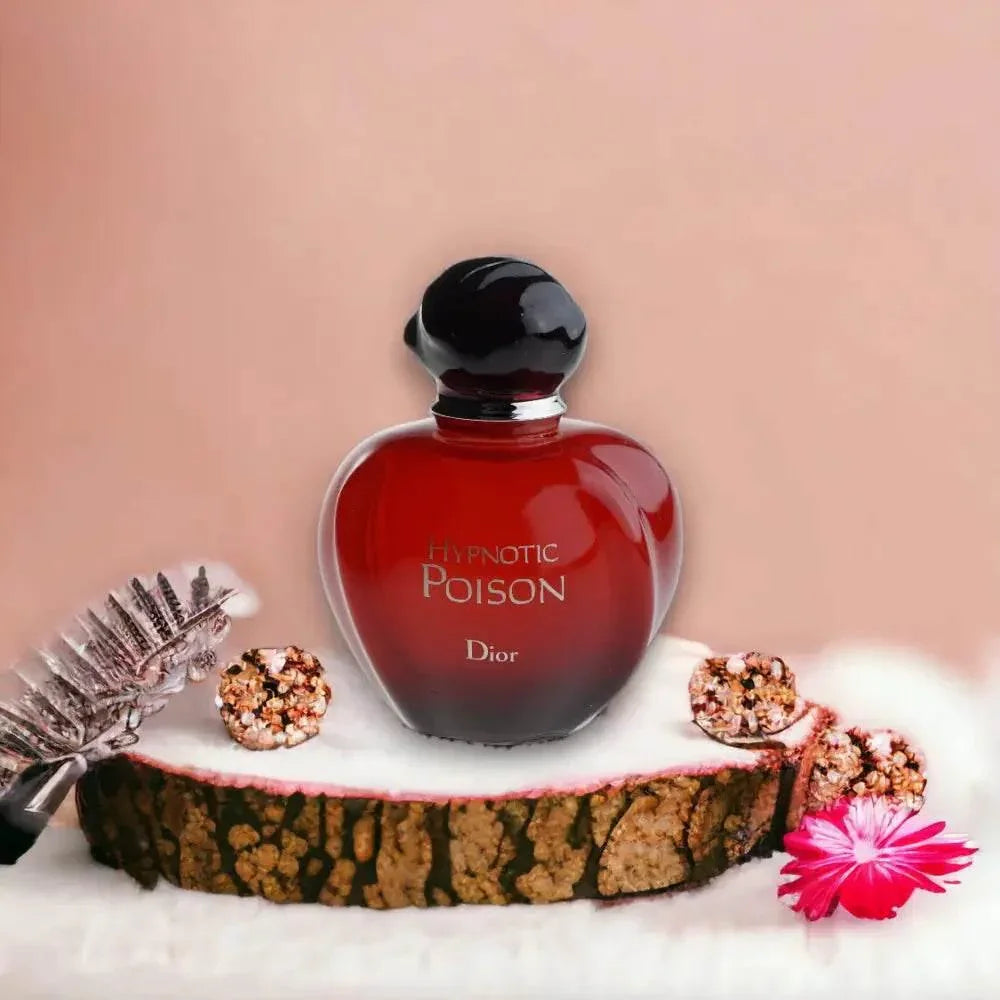 Rotes Hypnotic Poison Parfumflakon auf Baumscheibe mit Deko und Blüte, luxuriöses Damenparfum