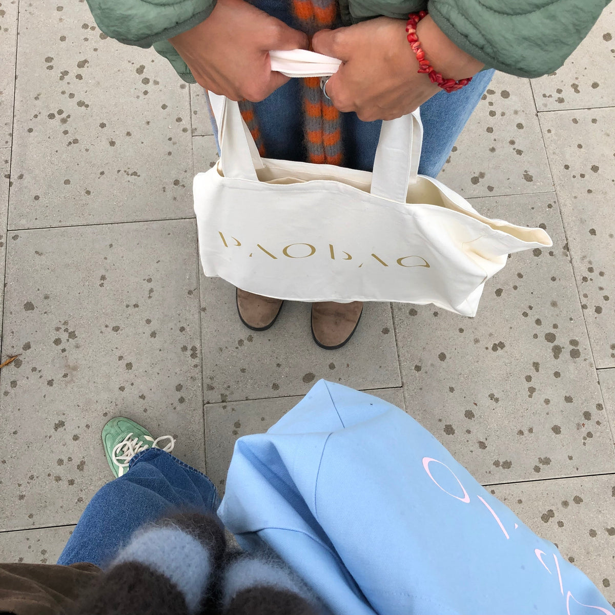 Weiße Tote Bag von paopao essentials in den Händen einer Person.