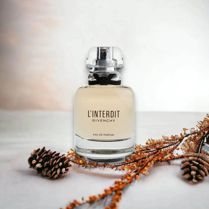 Luxusparfum Flakon L'Interdit Eau de Parfum auf hellem Hintergrund mit Zapfen und Zweigen