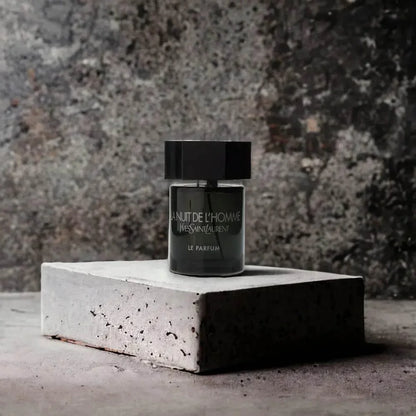 Edles Herrenparfum La Nuit De L'Homme Flakon auf Steinblock vor dunklem Hintergrund