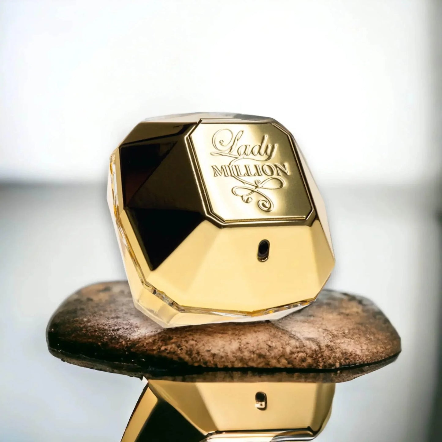 Goldener Lady Million Parfumflakon auf Stein, elegantes Luxus Damenparfum Produktbild