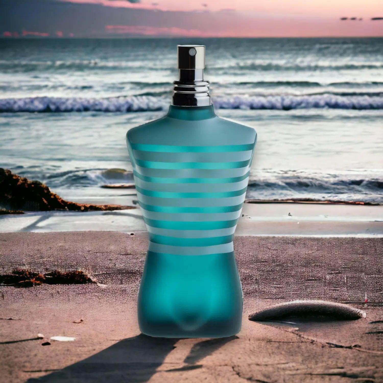 Blaues Herrenparfum in Körperform mit Streifenmuster am Strand vor Meer und Sonnenuntergang