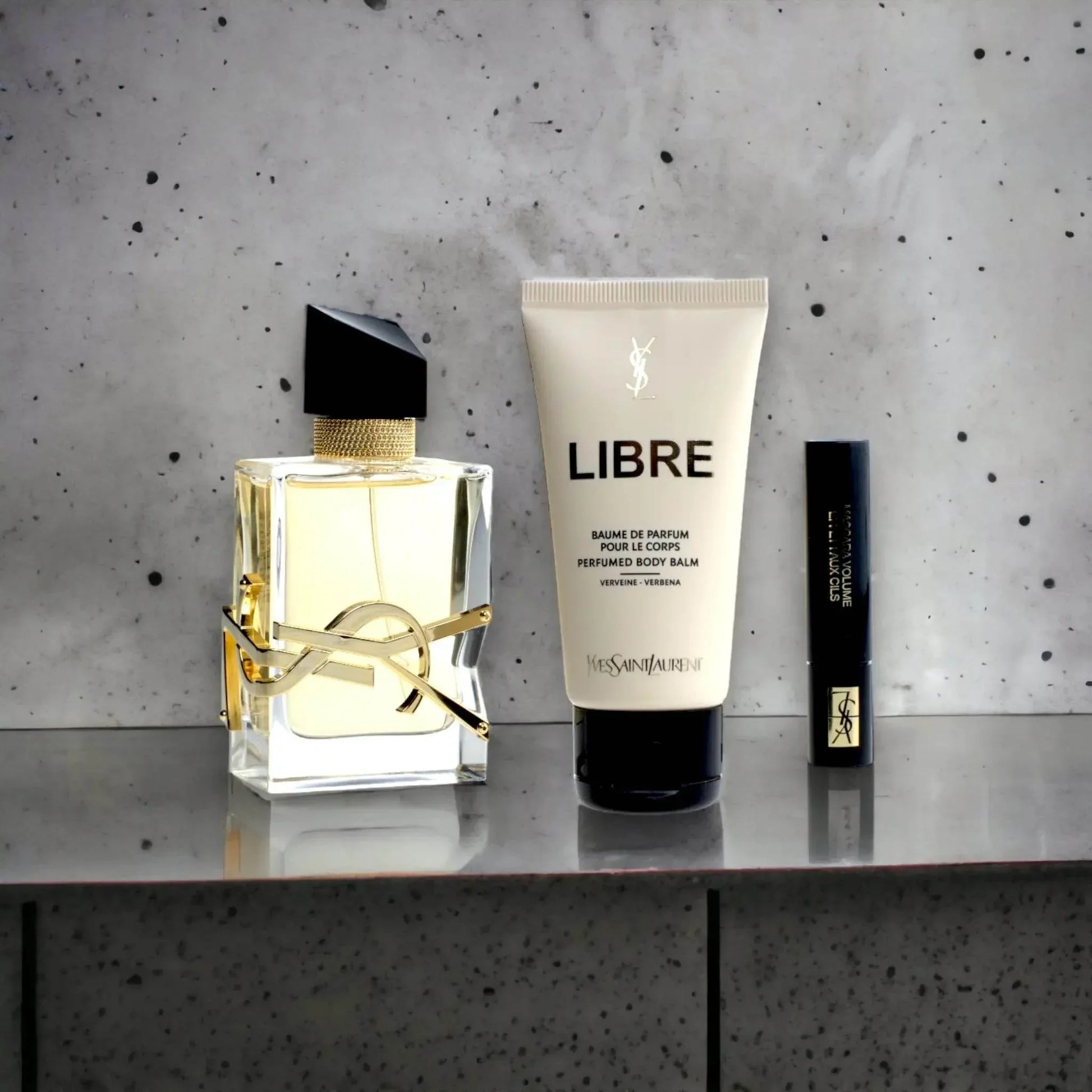 Parfum Geschenkset mit Flakon, Body Balm und Mascara auf grauem Hintergrund