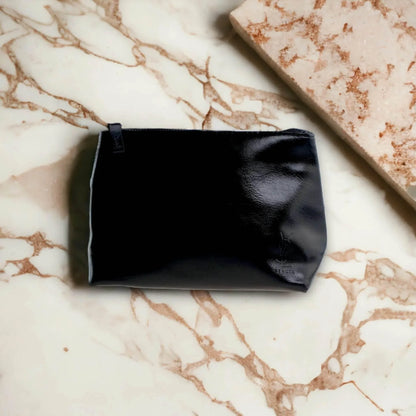 Schwarze Kosmetiktasche aus Lederoptik auf Marmoruntergrund, stilvoll und modern.