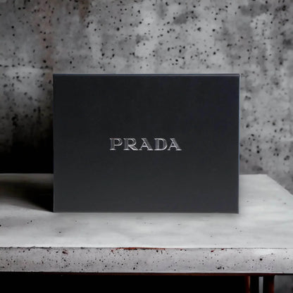 Edle schwarze PRADA Geschenkbox, luxuriöses Parfum Set auf hellem Tisch vor Steinwand.