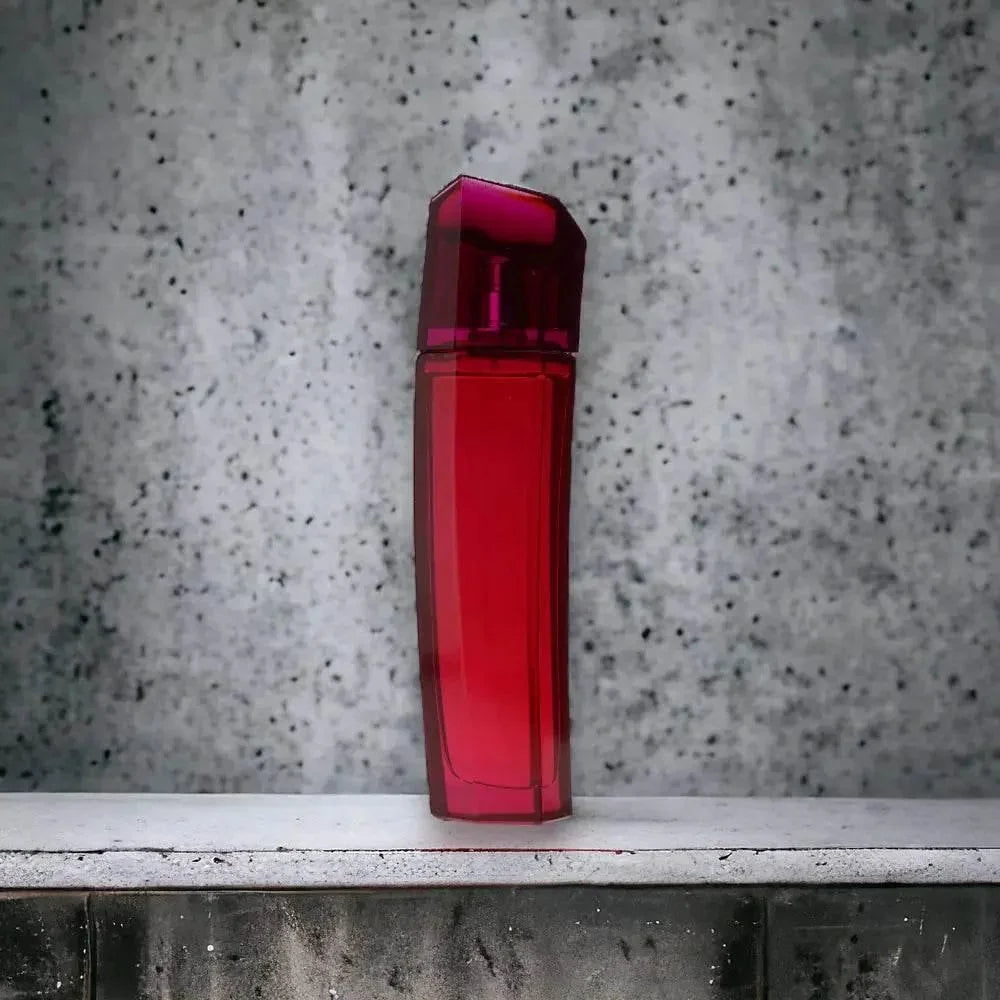 Roter Flakon des Escada Magnetism Eau de Parfum vor einer grauen Betonwand.