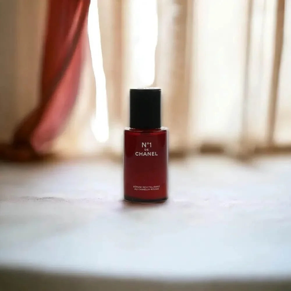 Ein roter Flakon des Chanel N°1 de Chanel Red Camellia Revitalizing Serum vor hellem Hintergrund.