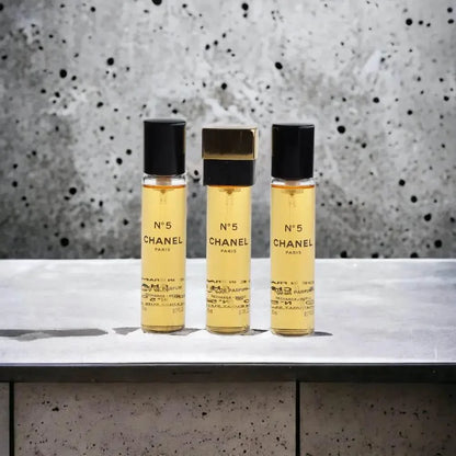 Drei Flakons N°5 Eau de Parfum stehen auf Beton, luxuriöses Damenparfum, elegantes Design
