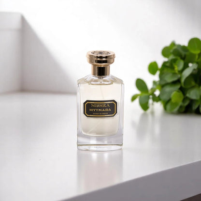 Luxus Parfumflakon Nishra Mythara auf heller Oberfläche mit grünem Pflanzenhintergrund