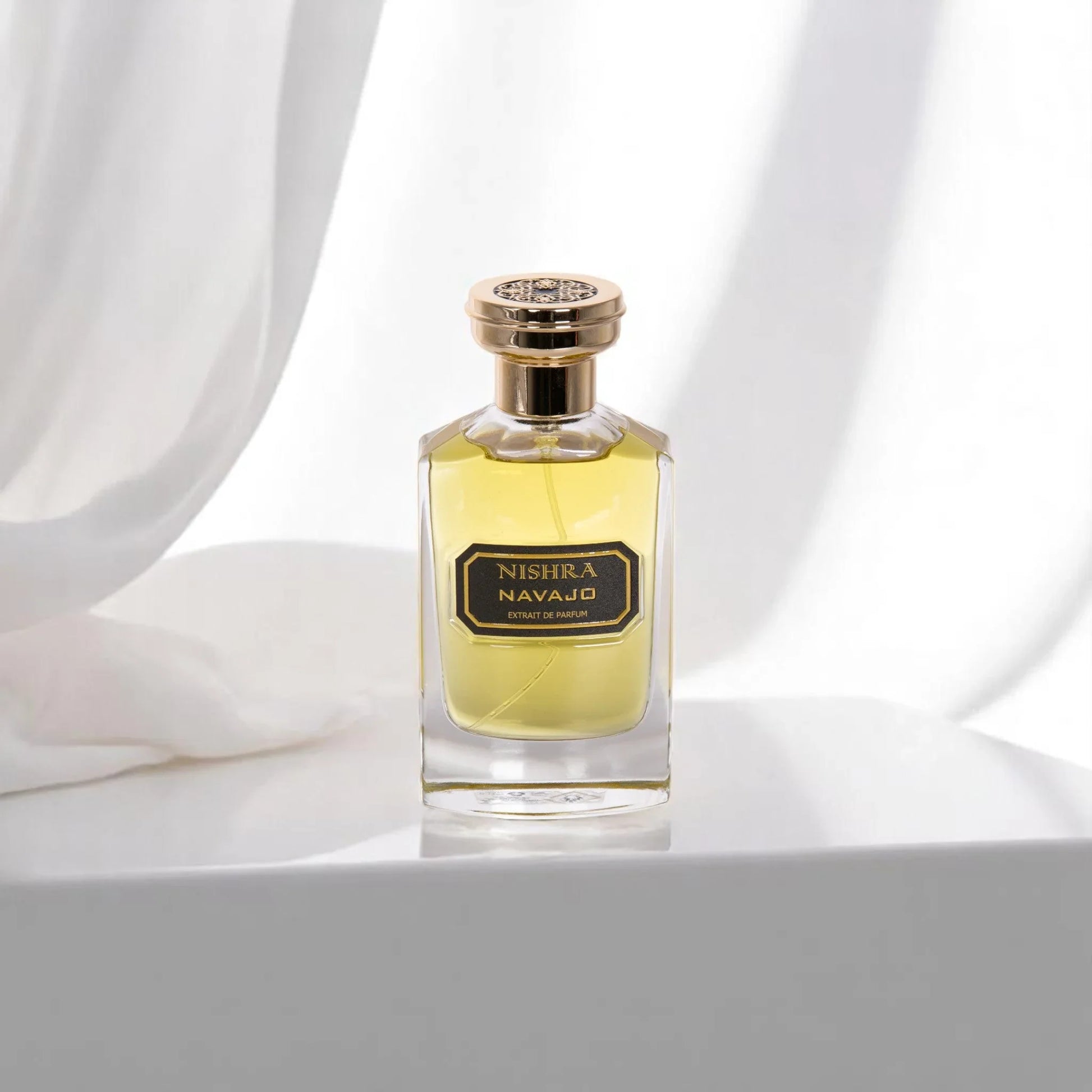 Luxus Parfumflakon Nishra Navajo mit goldener Kappe vor weißem, elegantem Hintergrund