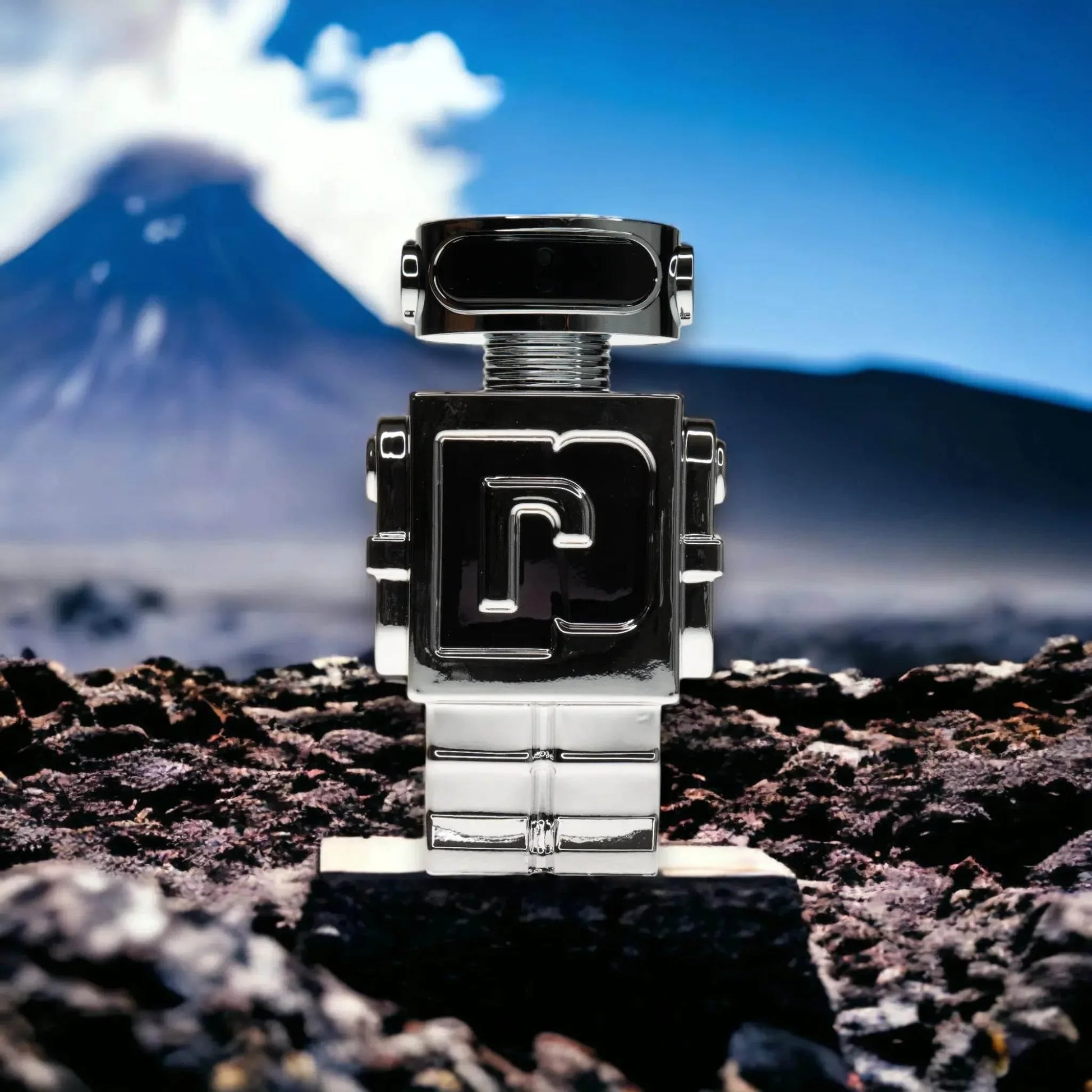 Silberner Parfümflakon in Roboterform auf vulkanischem Gestein vor Bergkulisse