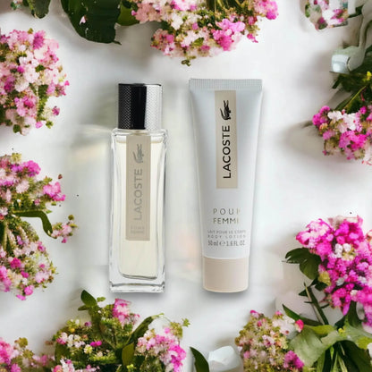 Lacoste Pour Femme Damenparfüm und Bodylotion Set, umgeben von rosa Blüten.