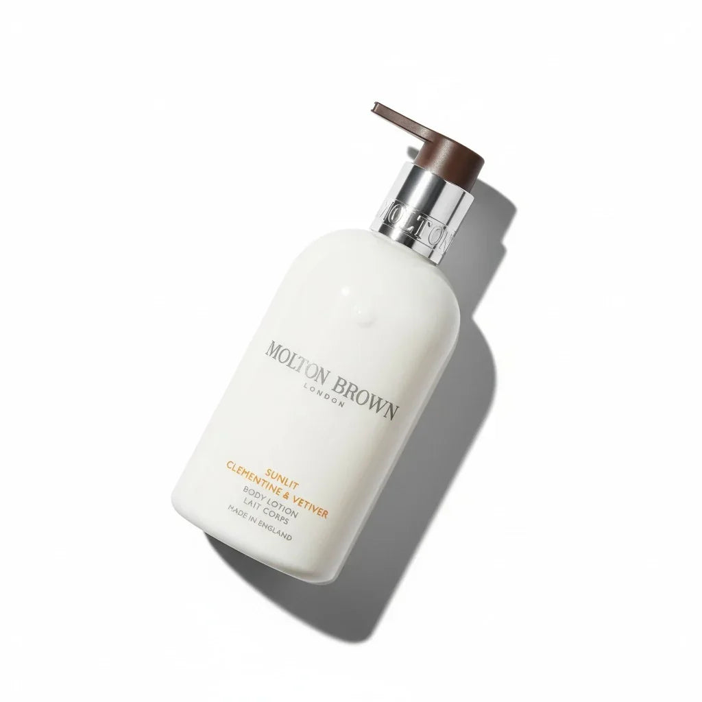 Weiße Molton Brown Sunlit Clementine & Vetiver Body Lotion Flasche mit Pumpspender.