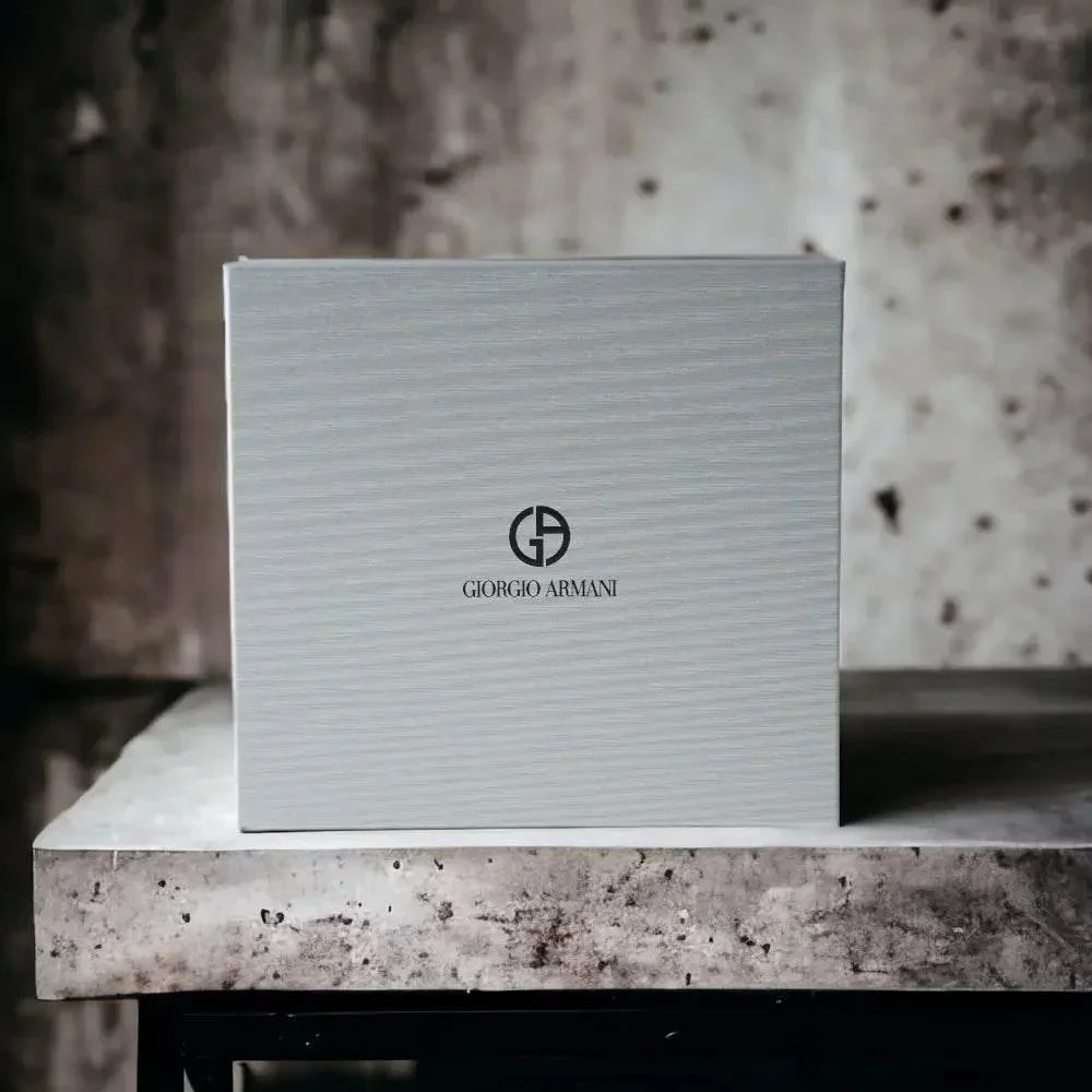 Weiße Parfüm-Geschenkbox mit Giorgio Armani Logo auf steinigem Tisch, luxuriöses Ambiente