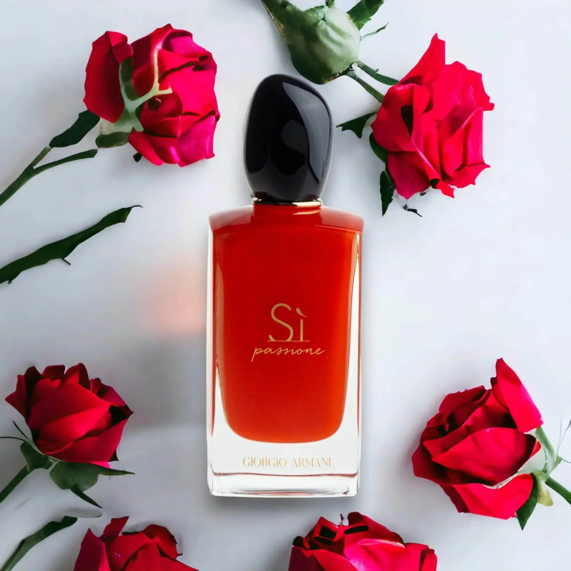 Rotes Parfumflakon mit schwarzem Deckel und goldener Aufschrift, umgeben von roten Rosen