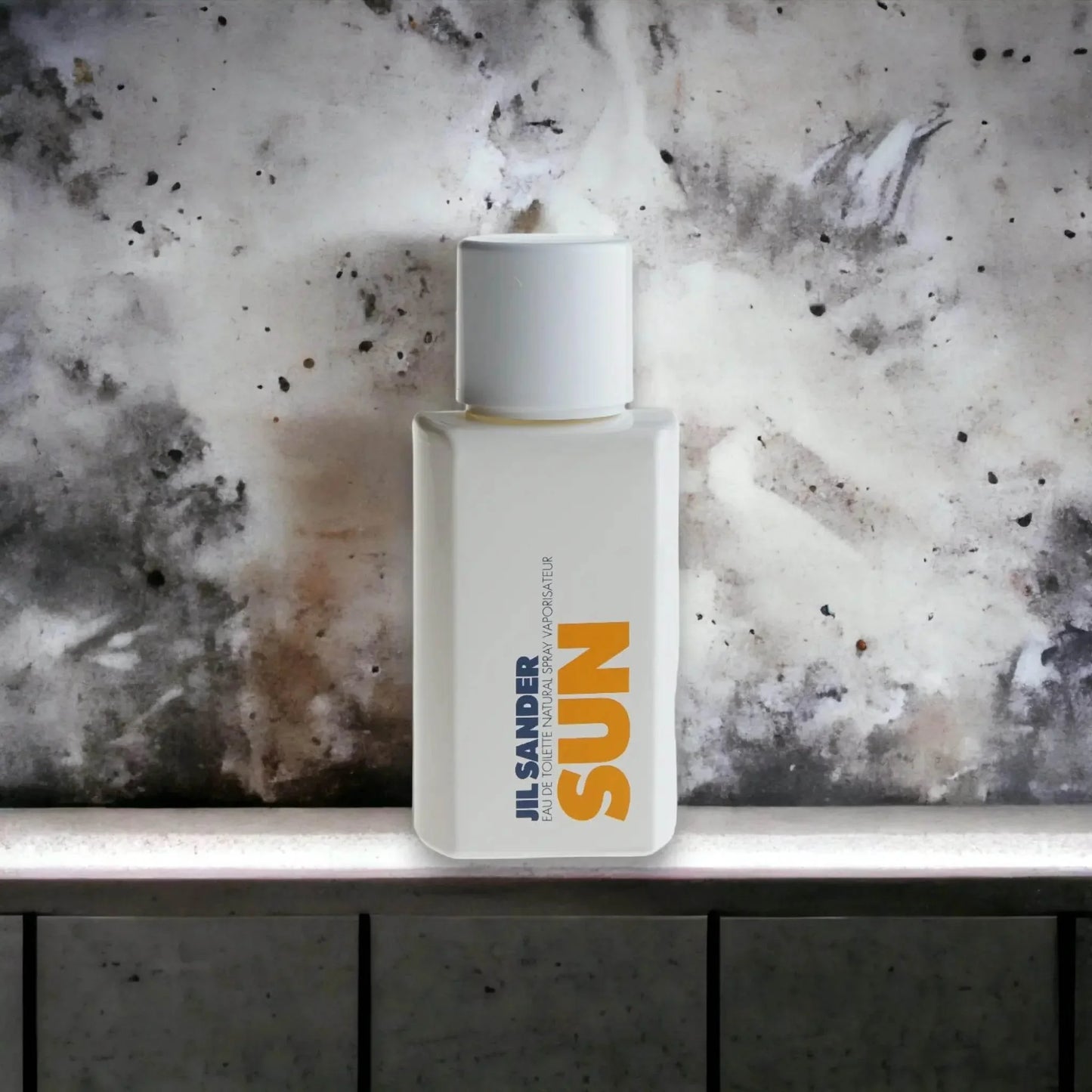 Jil Sander Sun Eau de Toilette Flakon vor marmorierter Wand, modernes Parfumdesign