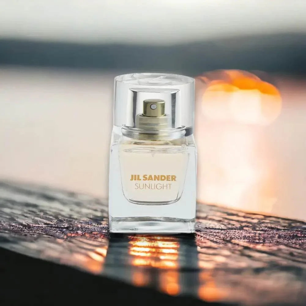Jil Sander Sunlight Eau de Parfum Flakon auf reflektierender Oberfläche vor Sonnenuntergang