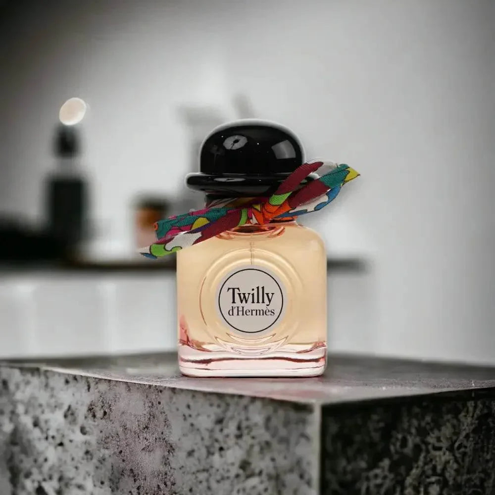 Twilly d'Hermès Eau de Parfum Flakon mit bunter Schleife auf Steinplatte, luxuriöses Damenparfum