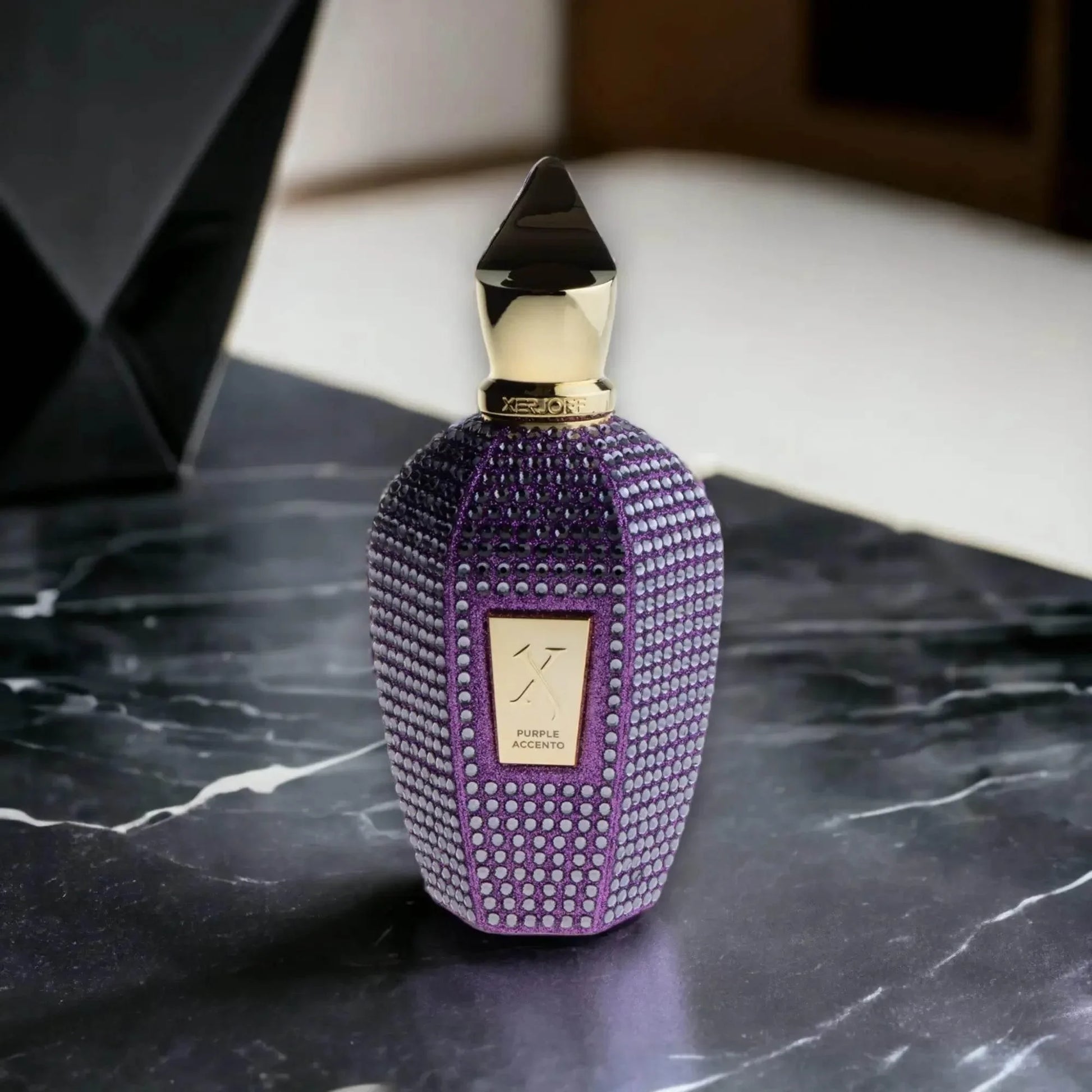 Lila Luxusparfumflakon mit goldenen Details und Kristallverzierung auf Marmortisch