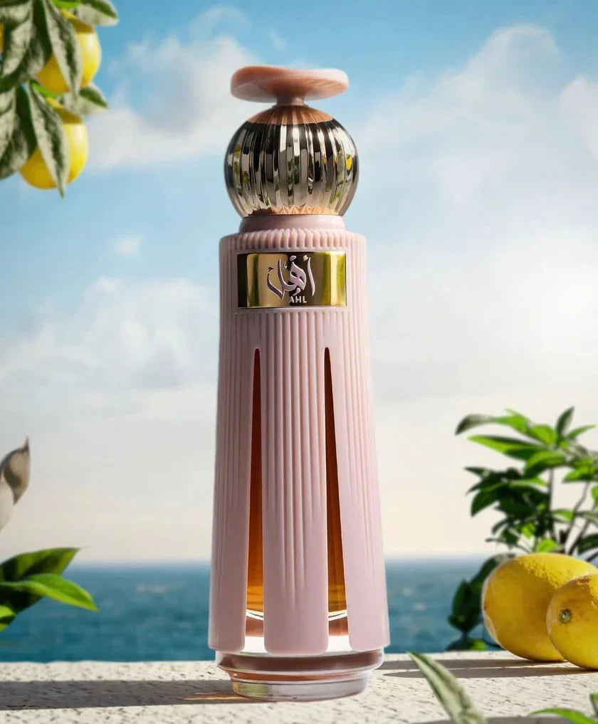 Luxusparfum Flakon in Rosa und Gold vor Meereshintergrund mit Zitronen, exklusiver Duft