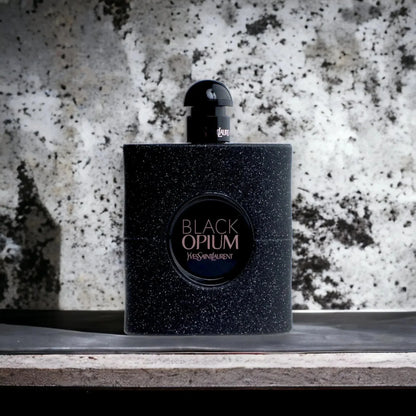 Luxuriöses schwarzes Parfumflakon Black Opium mit Glitzereffekt vor Marmorhintergrund