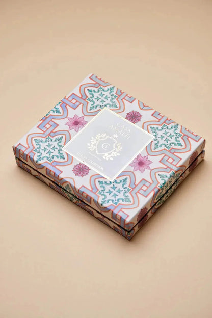 Bunt gemustertes Geschenkset mit Blumenmotiven und luxuriöser Verpackung auf beigem Hintergrund.